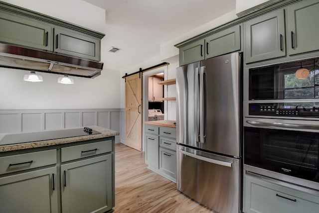 510 Daffodil St, Lake Jackson, TX 77566 - kitchen with black appliances, a barn door, light wood-type flooring, light countertops, and wainscoting