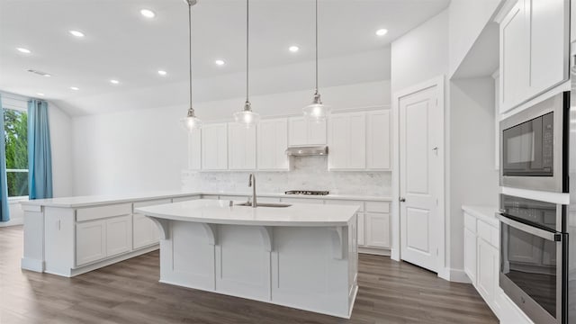 15139 Botanical Garden Dr, Conroe, TX 77302 - kitchen with black microwave, tasteful backsplash, gas stovetop, under cabinet range hood, and oven