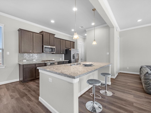 9618 Cambridge Manor Ln, Houston, TX 77045 - kitchen with appliances with stainless steel finishes, dark wood-style flooring, ornamental molding, dark brown cabinetry, and a kitchen breakfast bar