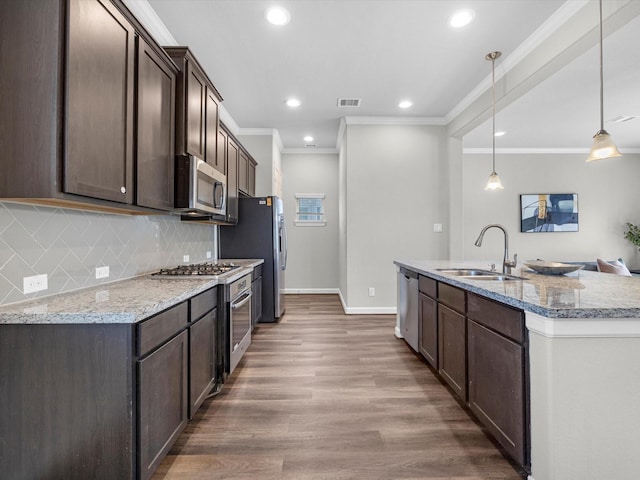 9618 Cambridge Manor Ln, Houston, TX 77045 - kitchen featuring dark brown cabinets, stainless steel appliances, crown molding, recessed lighting, and a kitchen island with sink