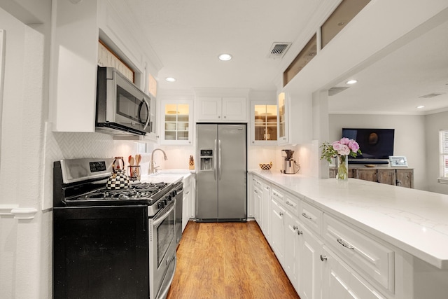 1838 Saxon Dr, Houston, TX 77018 - kitchen with stainless steel appliances, ornamental molding, a peninsula, glass insert cabinets, and recessed lighting
