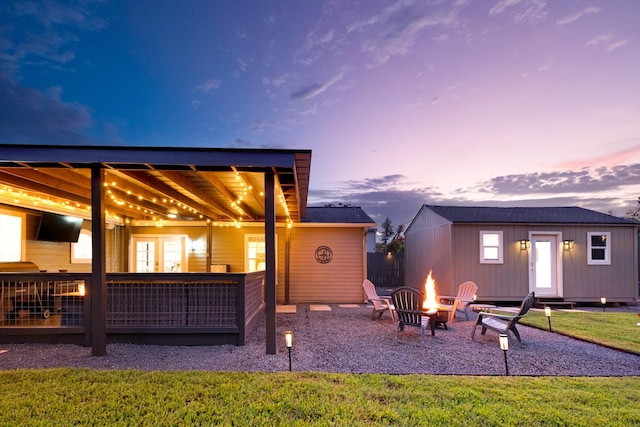 1838 Saxon Dr, Houston, TX 77018 - back of property at dusk with an outdoor fire pit, an outdoor structure, french doors, and a lawn