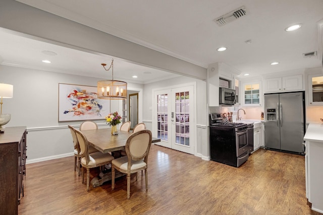 1838 Saxon Dr, Houston, TX 77018 - dining area featuring wood finished floors, crown molding, french doors, recessed lighting, and a chandelier