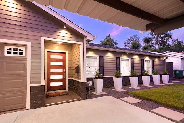 1838 Saxon Dr, Houston, TX 77018 - exterior entry at dusk with stone siding, a garage, and a patio