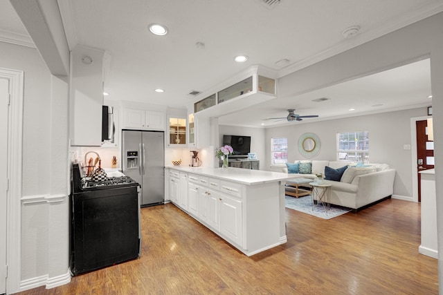 1838 Saxon Dr, Houston, TX 77018 - kitchen featuring stainless steel fridge, a peninsula, crown molding, black range with gas stovetop, and ceiling fan