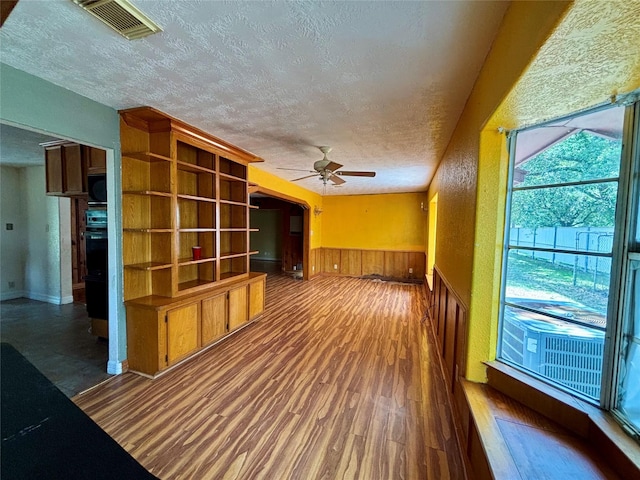 7947 Moore Dr, Pearland, TX 77584 - unfurnished living room featuring a textured ceiling, a ceiling fan, wood finished floors, wainscoting, and wooden walls