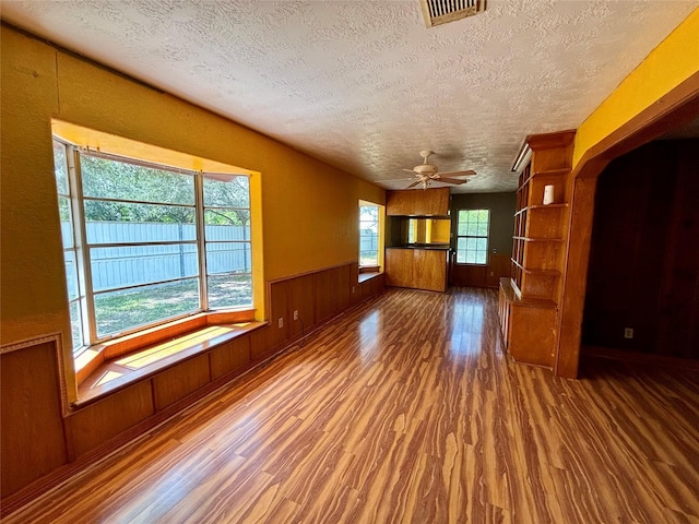 7947 Moore Dr, Pearland, TX 77584 - empty room with wood finished floors, a textured ceiling, a ceiling fan, a wainscoted wall, and wooden walls