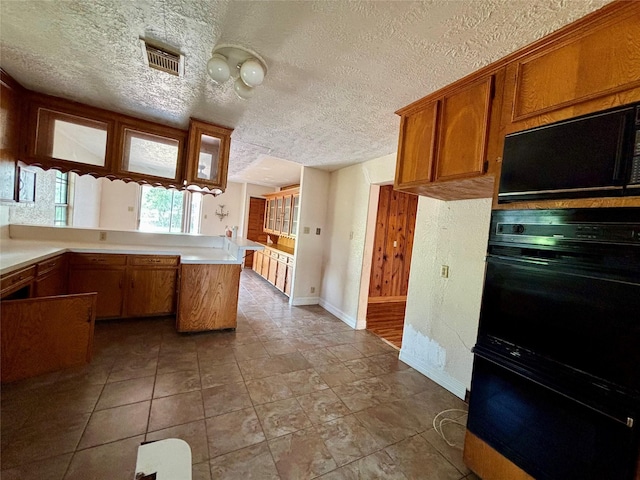 7947 Moore Dr, Pearland, TX 77584 - kitchen featuring brown cabinetry, a textured ceiling, light countertops, and a peninsula