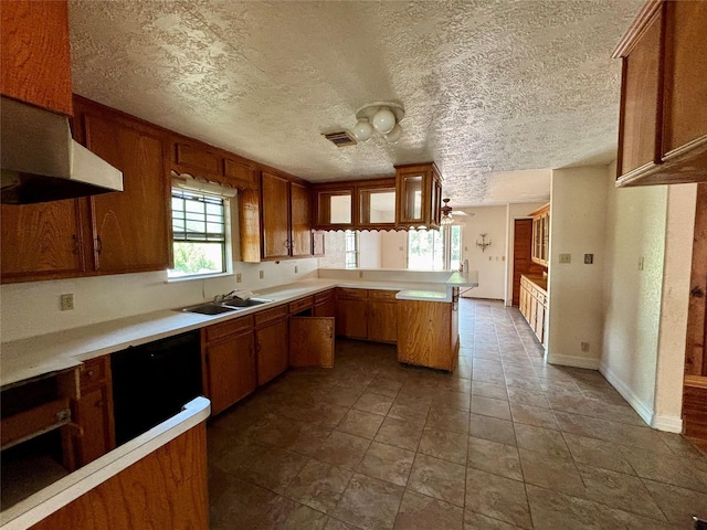 7947 Moore Dr, Pearland, TX 77584 - kitchen featuring a peninsula, brown cabinets, black dishwasher, light countertops, and a textured ceiling