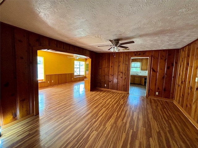 7947 Moore Dr, Pearland, TX 77584 - empty room featuring ceiling fan, wooden walls, wood finished floors, a textured ceiling, and arched walkways