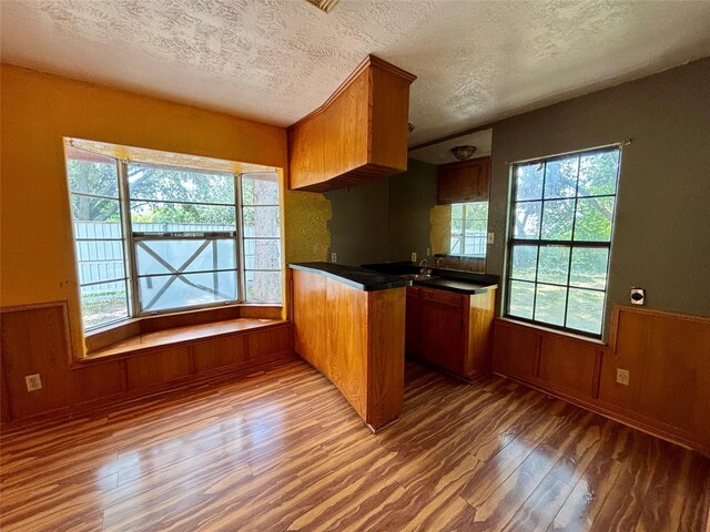 7947 Moore Dr, Pearland, TX 77584 - kitchen featuring wood finished floors, a textured ceiling, plenty of natural light, dark countertops, and brown cabinetry
