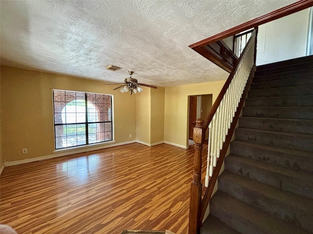 7947 Moore Dr, Pearland, TX 77584 - unfurnished living room featuring a textured ceiling, stairs, ceiling fan, and dark wood-style floors