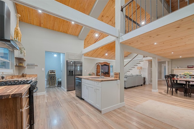 6170 Beech Dr, Montgomery, TX 77316 - kitchen featuring wood counters, gas range oven, wall chimney exhaust hood, a high ceiling, and open floor plan