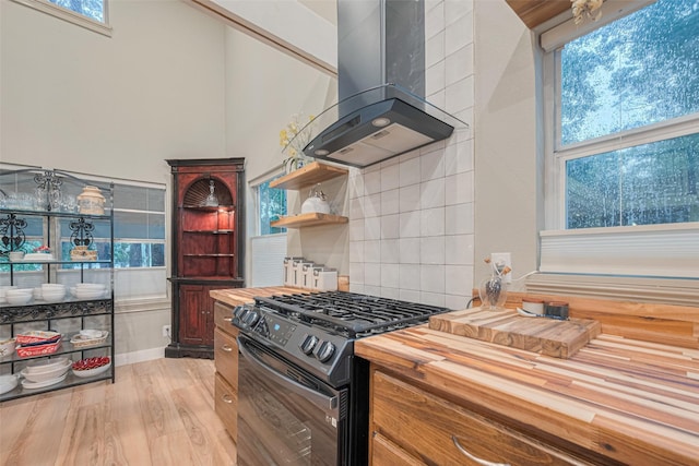6170 Beech Dr, Montgomery, TX 77316 - kitchen with stainless steel gas range, island exhaust hood, butcher block countertops, plenty of natural light, and a towering ceiling