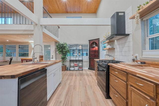 6170 Beech Dr, Montgomery, TX 77316 - kitchen with wood counters, dishwashing machine, black gas range oven, ventilation hood, and light wood-style floors