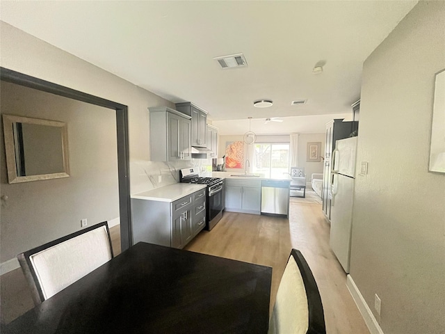 1502 Chilton Ln, Katy, TX 77493 - kitchen featuring gas range, a peninsula, freestanding refrigerator, gray cabinetry, and light wood-style floors