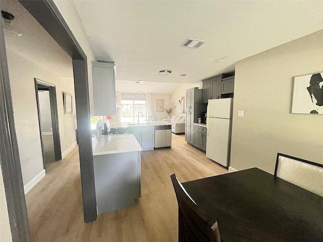 1502 Chilton Ln, Katy, TX 77493 - kitchen featuring freestanding refrigerator, light wood finished floors, a peninsula, light countertops, and gray cabinetry