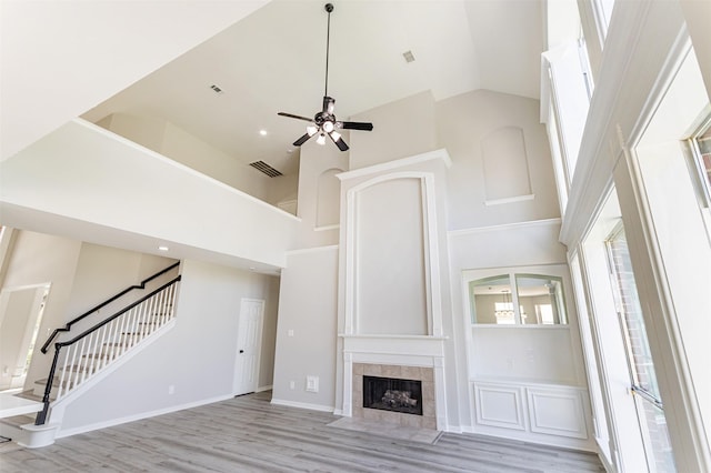 7147 Hot Creek Trce, Humble, TX 77346 - unfurnished living room with high vaulted ceiling, stairs, light wood-style flooring, ceiling fan, and a tiled fireplace