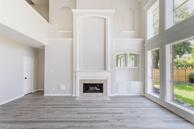 7147 Hot Creek Trce, Humble, TX 77346 - unfurnished living room featuring a towering ceiling, wood finished floors, and a fireplace