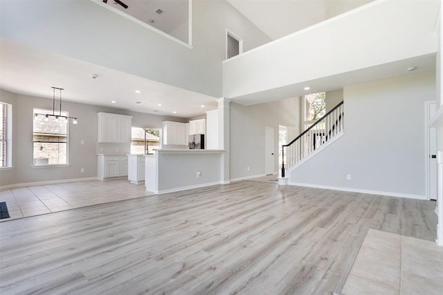 7147 Hot Creek Trce, Humble, TX 77346 - unfurnished living room featuring light wood-style flooring, a towering ceiling, stairway, recessed lighting, and a chandelier