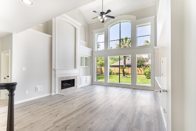 7147 Hot Creek Trce, Humble, TX 77346 - unfurnished living room with wood finished floors, high vaulted ceiling, a tile fireplace, ceiling fan, and recessed lighting