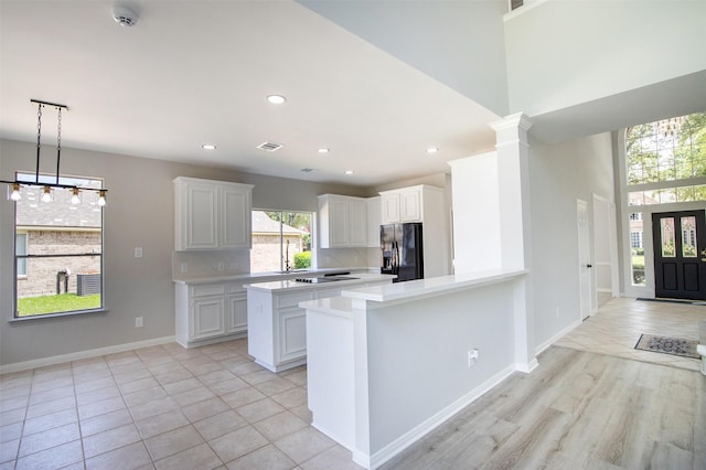 7147 Hot Creek Trce, Humble, TX 77346 - kitchen featuring black appliances, light countertops, a peninsula, hanging light fixtures, and white cabinets
