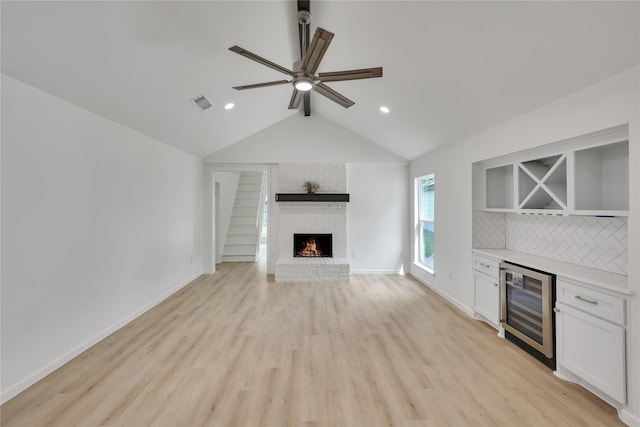 1503 Bamwick Dr, Houston, TX 77090 - unfurnished living room with beverage cooler, a bar, a ceiling fan, light wood-type flooring, and vaulted ceiling