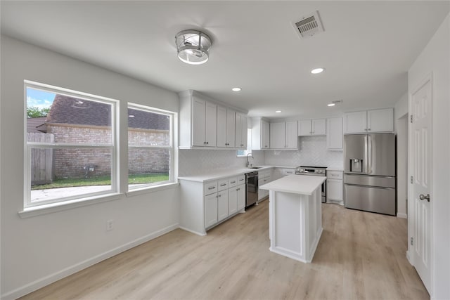 1503 Bamwick Dr, Houston, TX 77090 - kitchen with stainless steel appliances, light countertops, decorative backsplash, light wood-type flooring, and a kitchen island