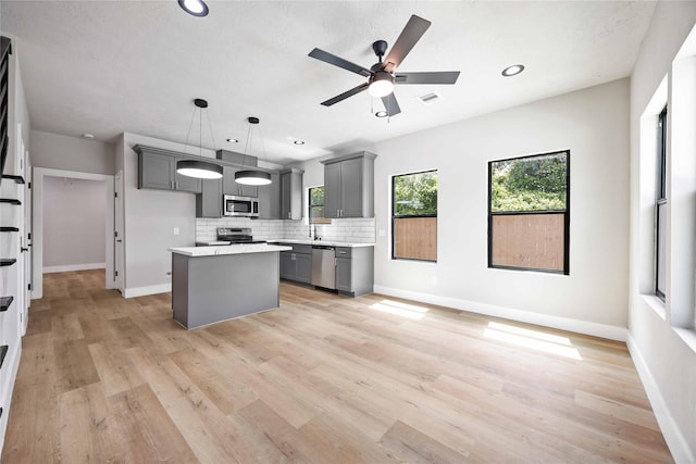 2409 Dolly Wright St, Houston, TX 77088 - kitchen with appliances with stainless steel finishes, gray cabinets, tasteful backsplash, a center island, and light countertops