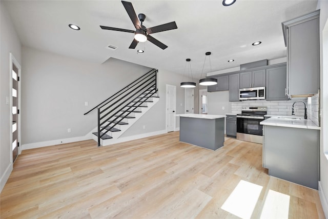 2409 Dolly Wright St, Houston, TX 77088 - kitchen with stainless steel appliances, a ceiling fan, gray cabinets, light countertops, and a center island