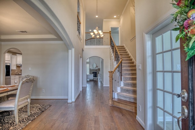 5506 Bellingen River Ln, Sugar Land, TX 77479 - entrance foyer with arched walkways, a chandelier, stairway, dark wood-type flooring, and crown molding