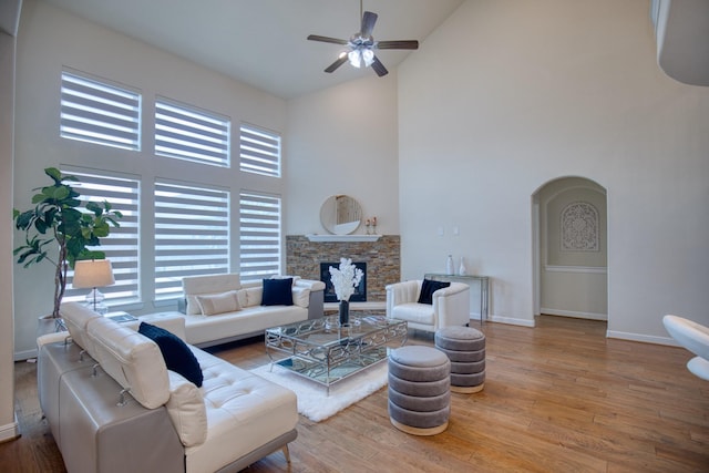 5506 Bellingen River Ln, Sugar Land, TX 77479 - living area with high vaulted ceiling, a ceiling fan, arched walkways, wood finished floors, and a stone fireplace