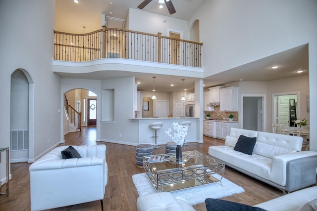 5506 Bellingen River Ln, Sugar Land, TX 77479 - living room featuring a high ceiling, ceiling fan, arched walkways, wood finished floors, and stairway