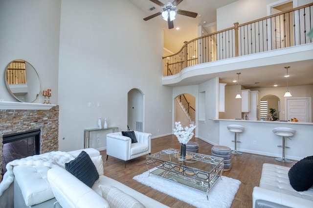 5506 Bellingen River Ln, Sugar Land, TX 77479 - living room featuring high vaulted ceiling, arched walkways, a ceiling fan, wood finished floors, and a stone fireplace