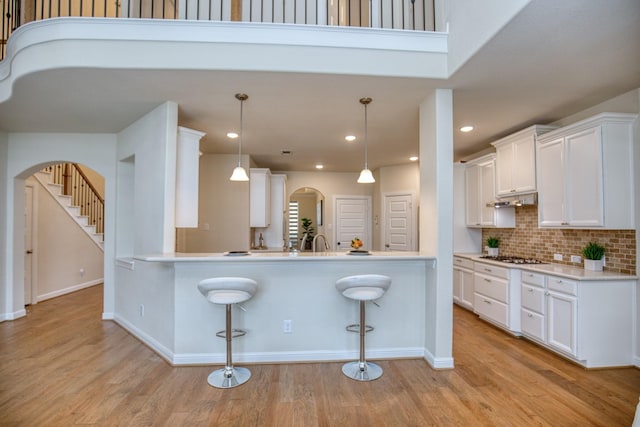 5506 Bellingen River Ln, Sugar Land, TX 77479 - kitchen featuring a breakfast bar area, arched walkways, white cabinetry, light wood finished floors, and recessed lighting