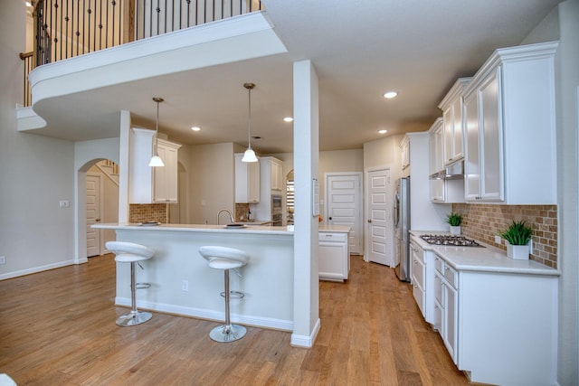 5506 Bellingen River Ln, Sugar Land, TX 77479 - kitchen with stainless steel appliances, arched walkways, a kitchen bar, under cabinet range hood, and tasteful backsplash