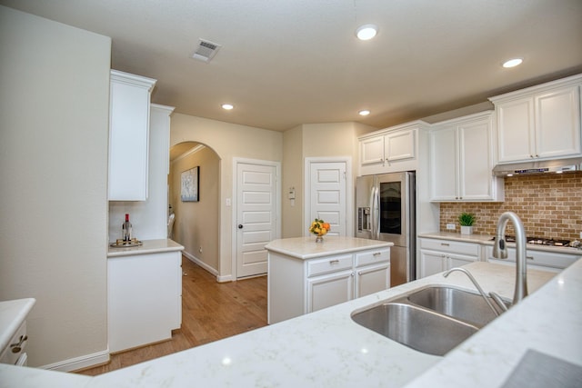 5506 Bellingen River Ln, Sugar Land, TX 77479 - kitchen with stainless steel refrigerator with ice dispenser, arched walkways, white cabinets, light wood-style flooring, and gas cooktop