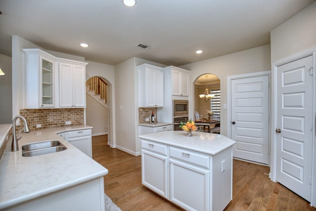 5506 Bellingen River Ln, Sugar Land, TX 77479 - kitchen with appliances with stainless steel finishes, arched walkways, backsplash, white cabinetry, and recessed lighting