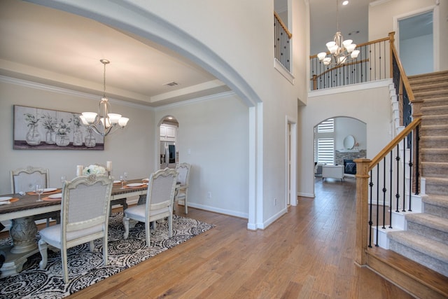 5506 Bellingen River Ln, Sugar Land, TX 77479 - dining room featuring a chandelier, arched walkways, stairway, wood finished floors, and ornamental molding