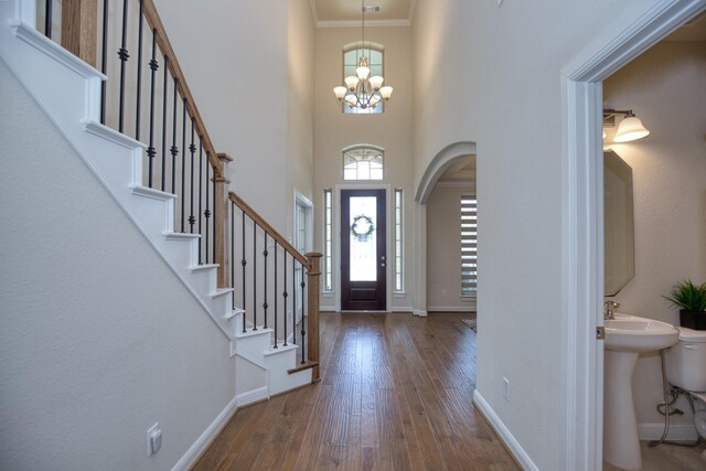 5506 Bellingen River Ln, Sugar Land, TX 77479 - foyer with dark wood-style flooring, a chandelier, ornamental molding, arched walkways, and a high ceiling