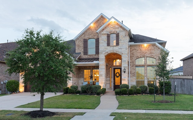 5506 Bellingen River Ln, Sugar Land, TX 77479 - french country inspired facade featuring concrete driveway, stone siding, a standing seam roof, brick siding, and a garage