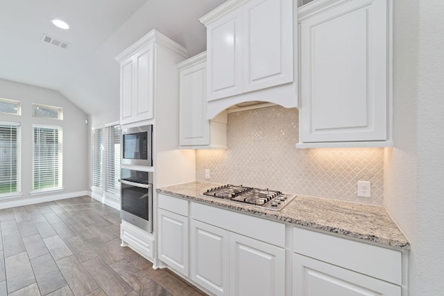 13727 Pedernales Ct, Cypress, TX 77429 - kitchen featuring stainless steel appliances, backsplash, lofted ceiling, white cabinetry, and light stone countertops