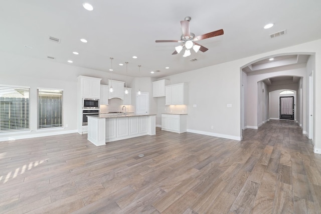 13727 Pedernales Ct, Cypress, TX 77429 - unfurnished living room with a ceiling fan, light wood-style floors, recessed lighting, and arched walkways