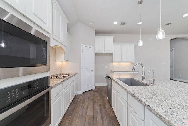 13727 Pedernales Ct, Cypress, TX 77429 - kitchen with appliances with stainless steel finishes, tasteful backsplash, arched walkways, dark wood-style flooring, and white cabinetry