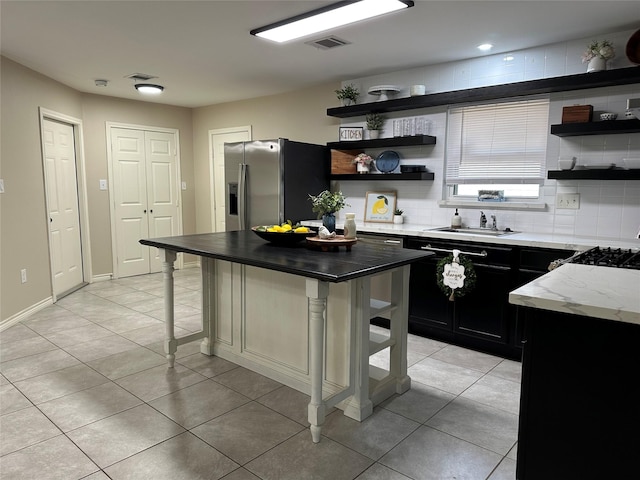 318 N 4th St, Alvin, TX 77511 - kitchen with open shelves, stainless steel fridge with ice dispenser, dark cabinets, and a breakfast bar area