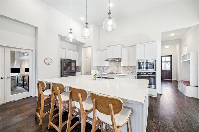 32311 Noble Creek Dr, Conroe, TX 77385 - kitchen with stainless steel appliances, tasteful backsplash, dark wood-type flooring, light countertops, and an island with sink