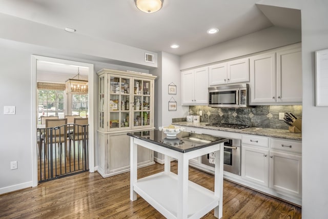 2717 University Blvd, Houston, TX 77005 - kitchen with stainless steel appliances, a chandelier, backsplash, light stone countertops, and white cabinets