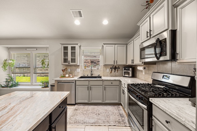 15003 Moonlight Mist Dr, Humble, TX 77346 - kitchen featuring appliances with stainless steel finishes, tasteful backsplash, gray cabinets, recessed lighting, and glass insert cabinets