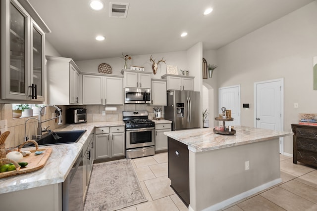15003 Moonlight Mist Dr, Humble, TX 77346 - kitchen with stainless steel appliances, a center island, tasteful backsplash, light tile patterned floors, and light stone counters