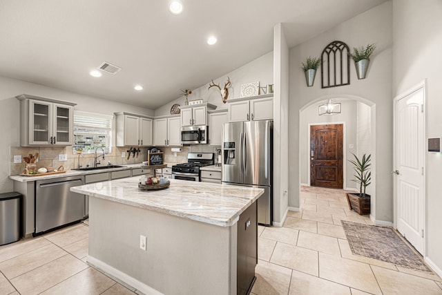 15003 Moonlight Mist Dr, Humble, TX 77346 - kitchen with appliances with stainless steel finishes, decorative backsplash, a kitchen island, light stone counters, and high vaulted ceiling